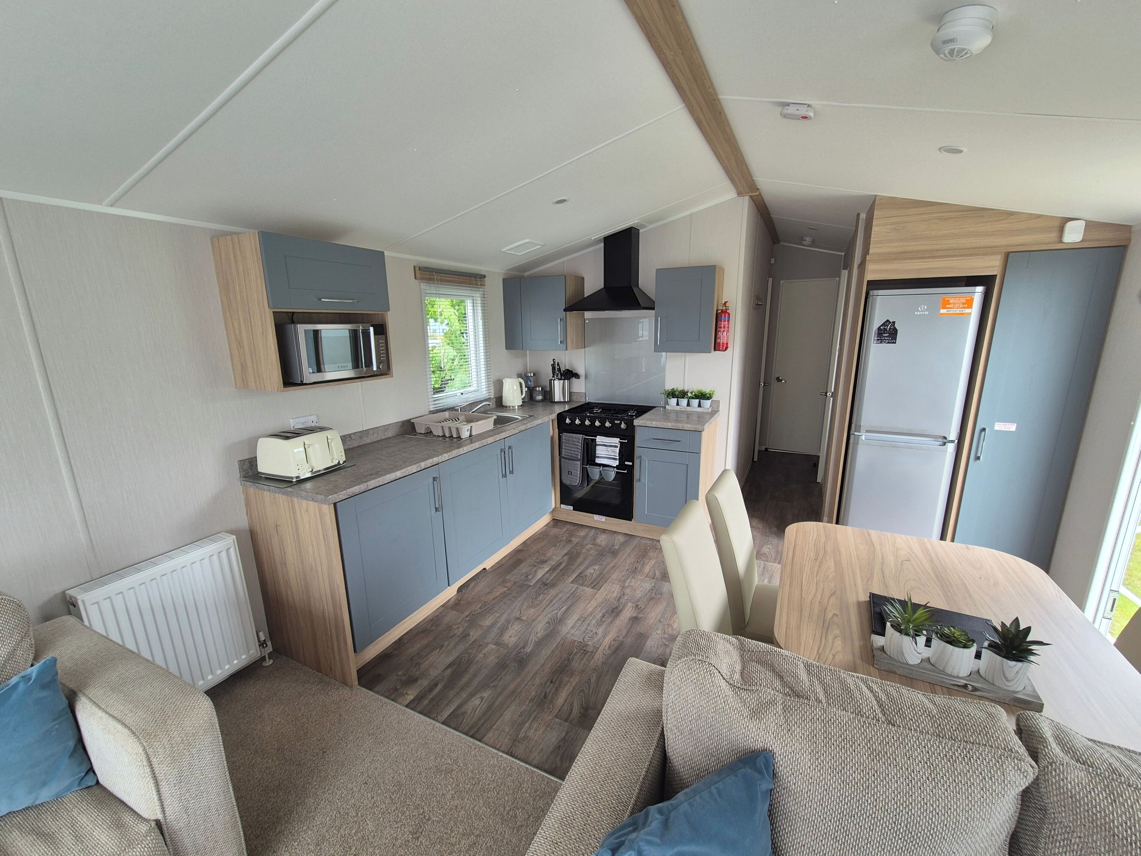A compact kitchen with a microwave, stove, and sink. There is a dining area with a table and chairs.