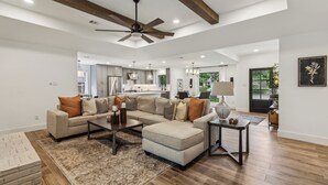 A spacious living room with a sectional sofa, a coffee table, and a ceiling fan.