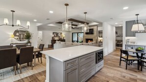 A modern kitchen with a large island, dining area, and a cozy living space with a fireplace.