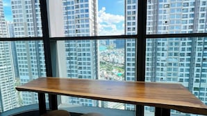 Habitación de esquina con un amplio ventanal que ofrece vistas a edificios altos y al paisaje urbano.