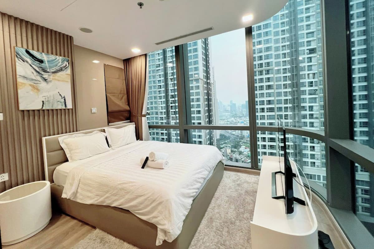 A modern hotel room with a large bed, a flat-screen TV, and a city view.