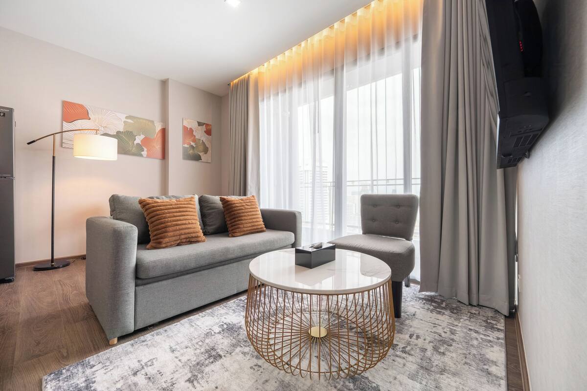 Un salon moderne avec un canapé gris, une table basse ronde et un lampadaire.