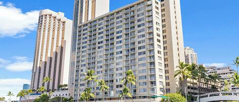 Un hotel frente al agua con varios edificios altos, un puerto deportivo con barcos y palmeras.