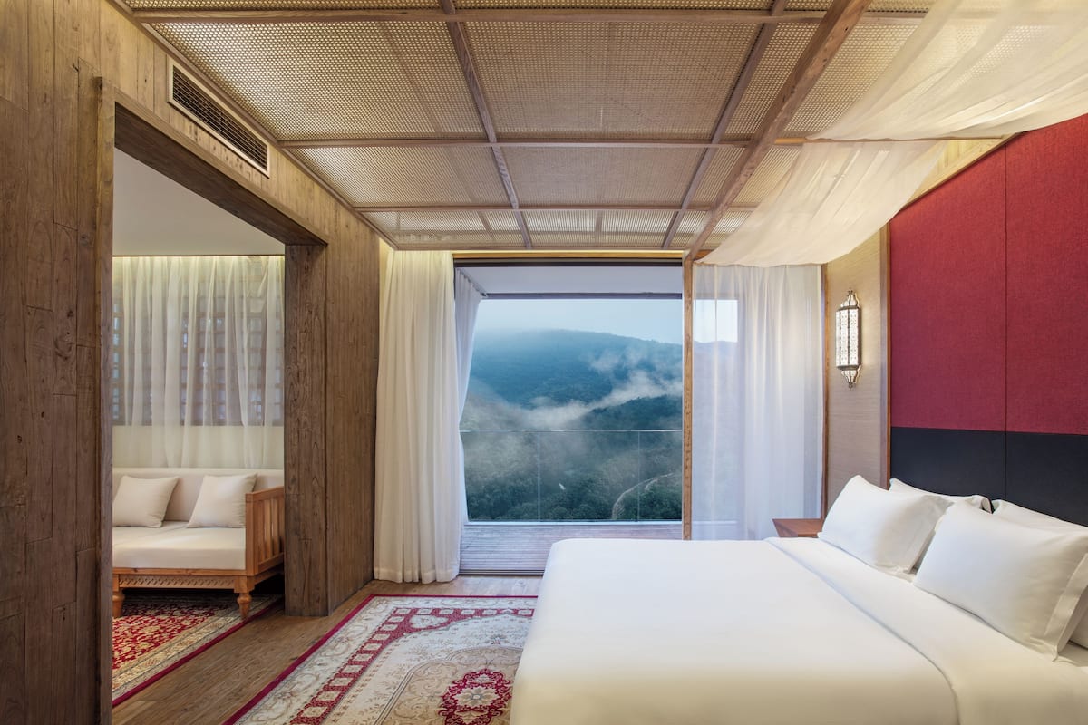 Camera da letto con un letto grande, vista sulle montagne e soffitto in legno.