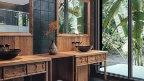 A modern bathroom with wooden cabinetry, a large mirror, and a window with a view of tropical plants. - Jinghong Bood Panorama Resort Inn (Xishuangbanna Dai)