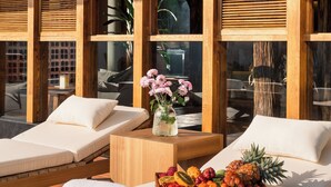 A sunlit room with wooden furniture, a fruit tray, and a vase of flowers. - Jinghong Bood Panorama Resort Inn (Xishuangbanna Dai)