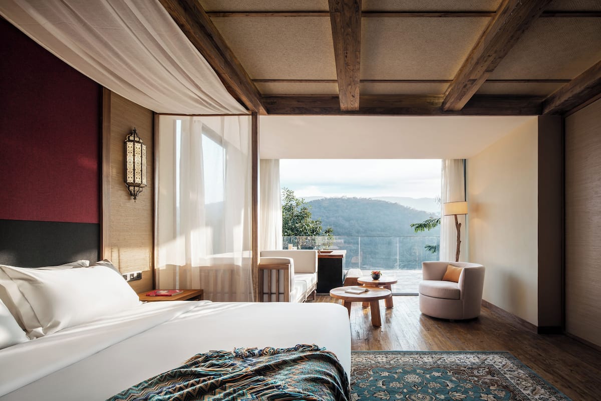 Una camera da letto con un ampio letto, vista all'esterno, un'area salotto e un balcone.