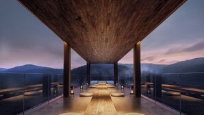 A spacious terrace with a wooden ceiling, glass railings, and a view of distant hills. - Jinghong Bood Panorama Resort Inn (Xishuangbanna Dai)