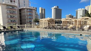 A swimming pool with lounge chairs and a view of high-rise buildings in the background. - Diamondhead & Ocean View ISLAND COLONY, Central location Walk to the beach, AC (Honolulu)