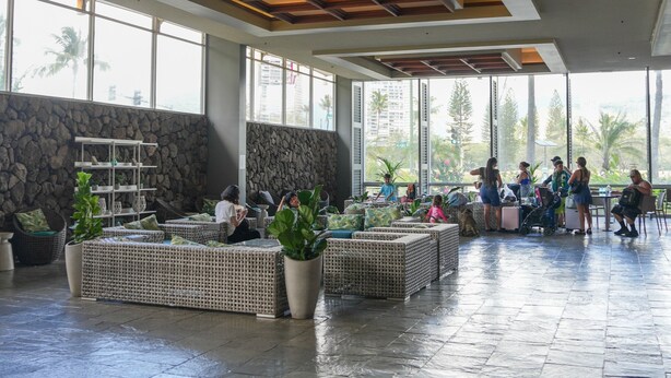A spacious lobby with a stone wall, large windows, and a seating area with planters. - Diamondhead & Ocean View ISLAND COLONY, Central location Walk to the beach, AC (Honolulu)