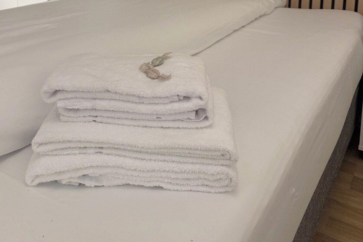 Una cama bien hecha con una toalla blanca doblada y un adorno sobre ella.