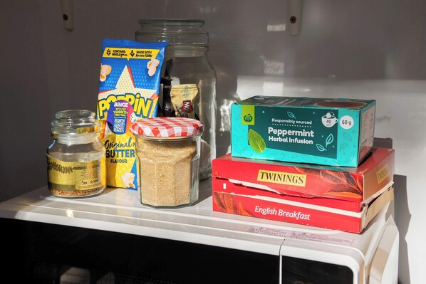 Un microondas con diversos alimentos y cajas encima.