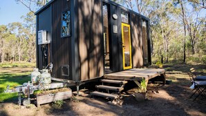 Una piccola baita con rivestimento in legno, una porta gialla e una piccola veranda.