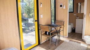 Una stanza compatta con un tavolo e sedie in legno, un angolo cottura e una porta scorrevole che dà su una terrazza esterna.
