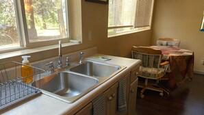 Una cocina con dos fregaderos de acero inoxidable, un escurreplatos y una mesa con mantel.