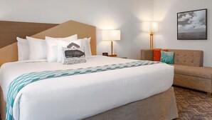 Een hotelkamer met een groot bed, een bank, een nachtkastje en een wandlamp.