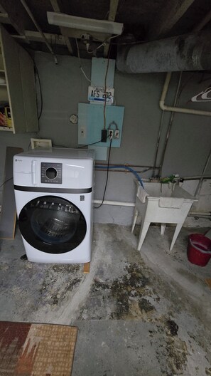 Uma lavanderia com máquina de lavar, armário de utilidades e uma pia pequena.