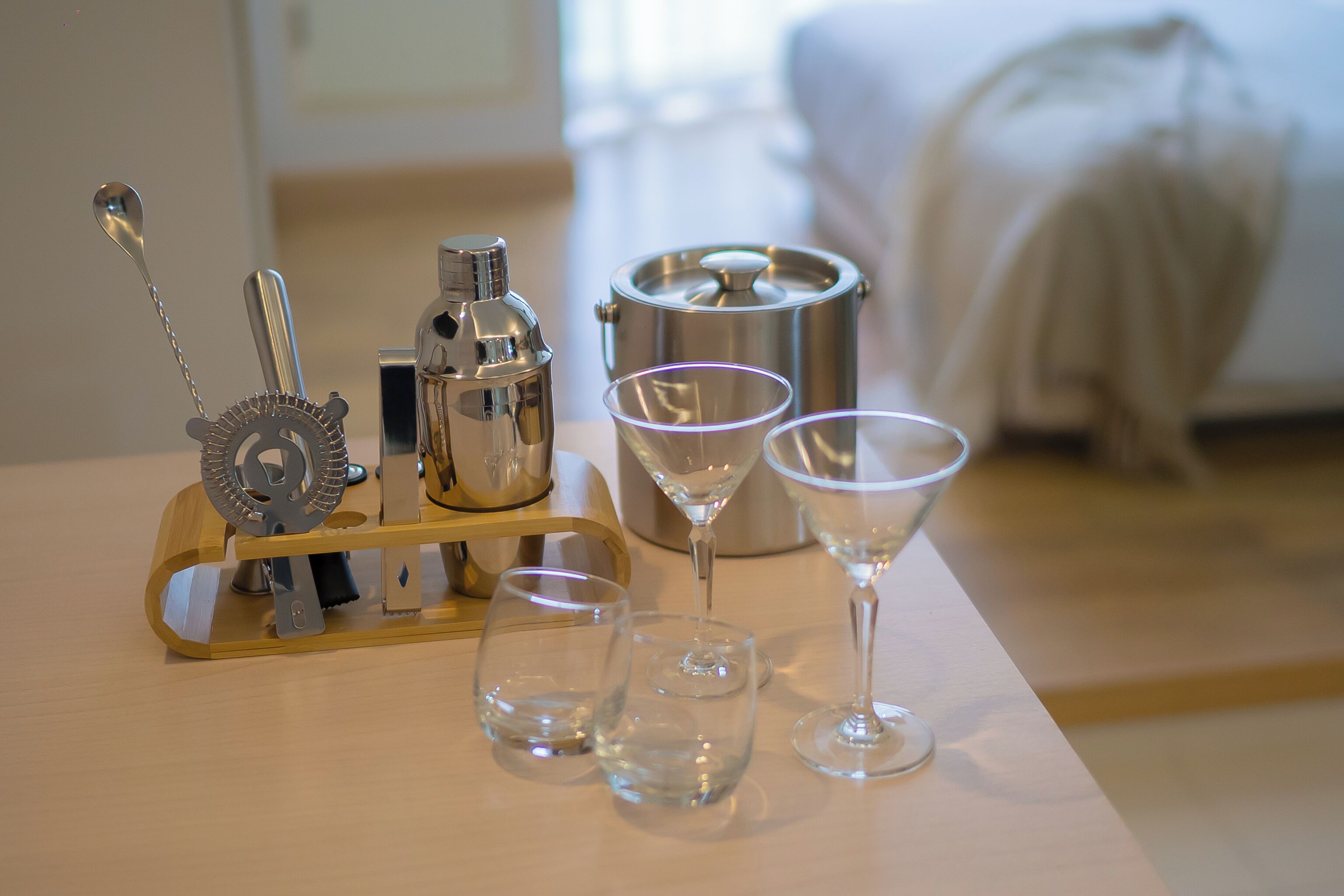 Et bord med en cocktailshaker, en flaske og tre martini-glas.