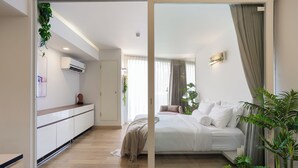 A modern bedroom with a large bed, bedside plants, and a sliding door leading to a bathroom. - Beachside Chic Coastal Hideaway (Hua Hin)