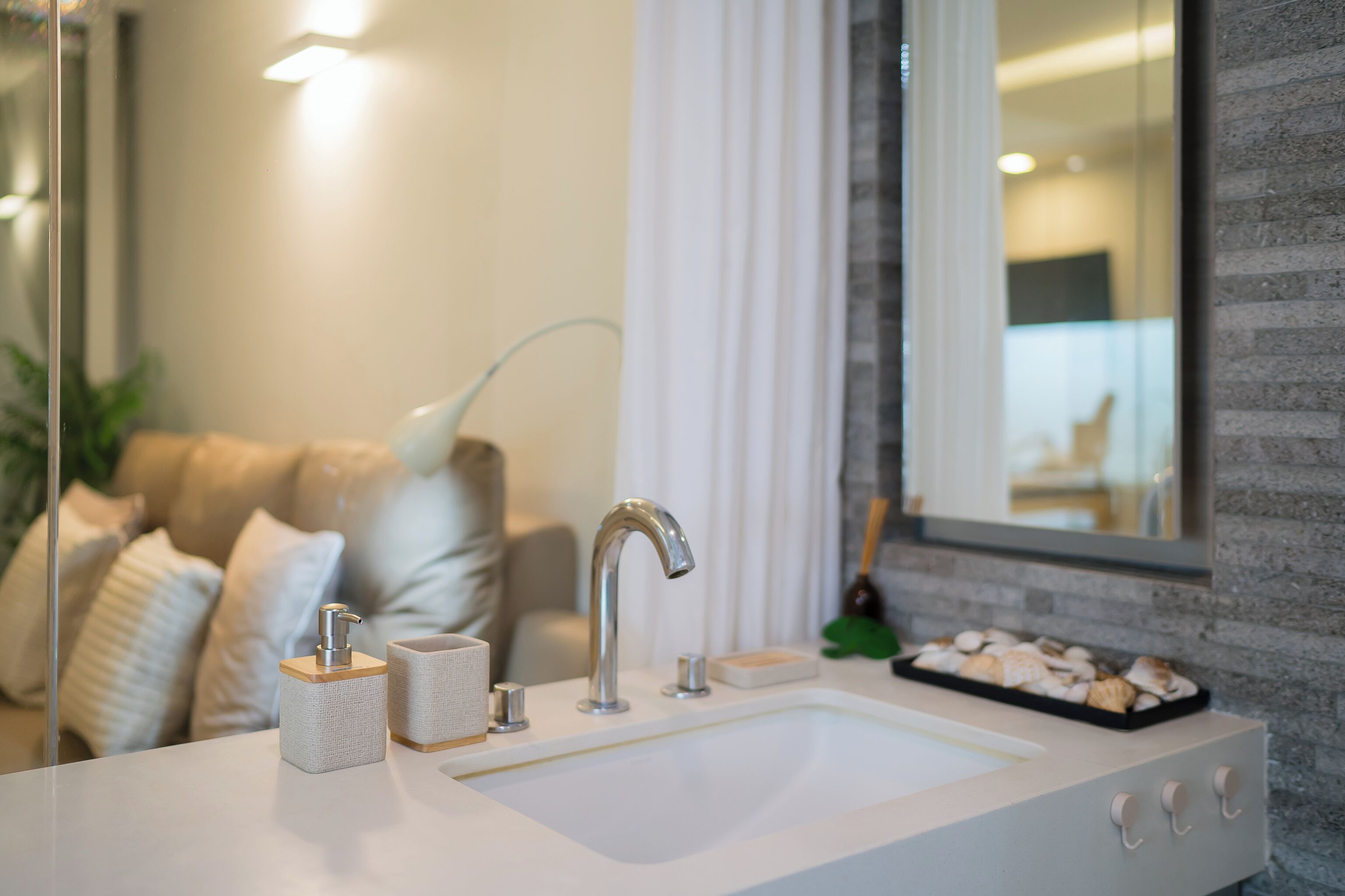 Un baño moderno con un lavamanos blanco, un grifo de cromo y un dispensador de jabón.