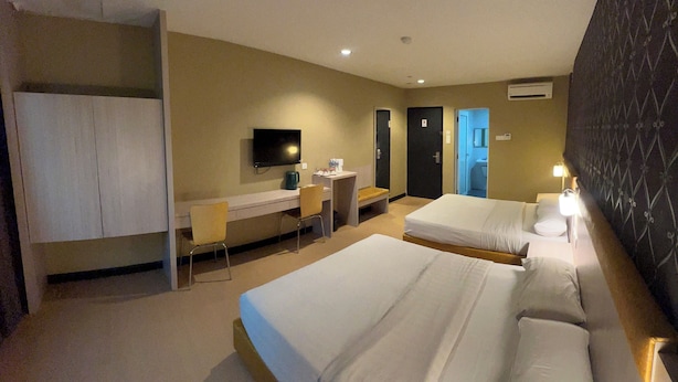 Une chambre d’hôtel avec deux lits, un bureau, une télévision et une armoire.