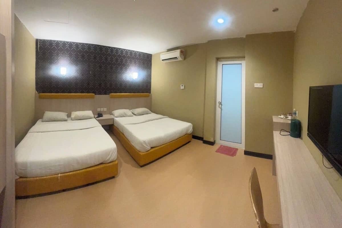 A hotel room with two beds, a TV, an air conditioning unit, and a door leading to another room.