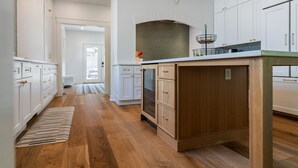 A modern kitchen with white cabinetry, a wooden island, and a brick backsplash.