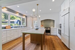 A modern kitchen with white cabinetry, a central island, and a brick backsplash.