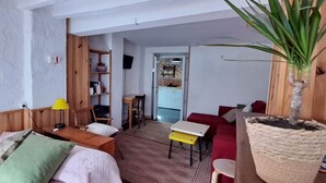 A cozy living room with a wooden sofa, a small table, a red armchair, and a potted plant. - Alhambrita. Cool and quiet house with wifi to disconnect. (Viznar)