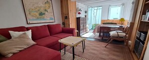 A cozy living room with a red sofa, a small table, and a map on the wall.