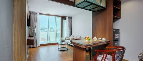 Une chambre d’hôtel moderne avec un plancher en bois, un coin repas doté d’un comptoir en marbre, une chaise en bois et une grande fenêtre donnant sur la ville.