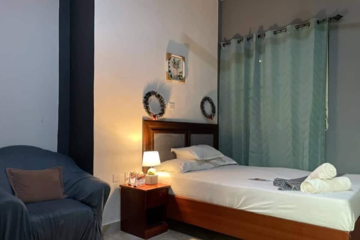 A bedroom with a bed, a nightstand, a chair, and two wall decorations.
