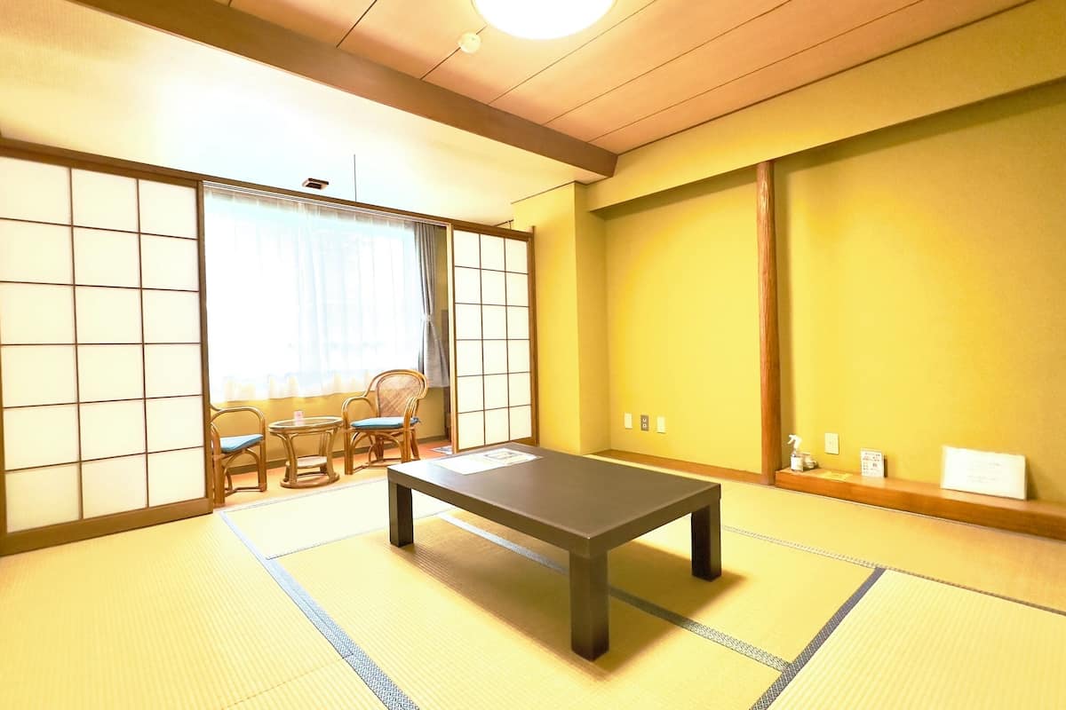 Une pièce de style japonais traditionnel, avec un sol recouvert de tatamis, une table basse et des portes coulissantes.