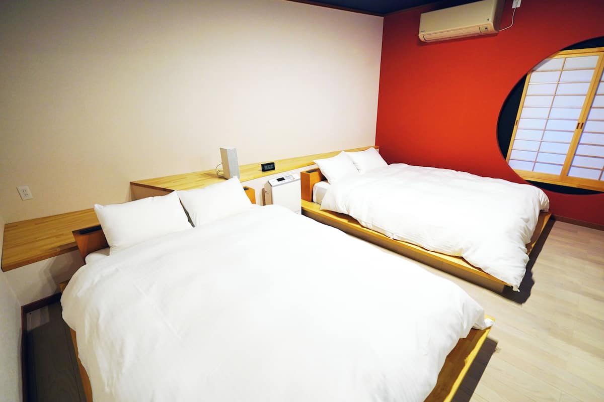Une chambre d’hôtel avec deux lits, une tête de lit en bois, un mur d’accent rouge et une fenêtre donnant sur un paysage agréable.