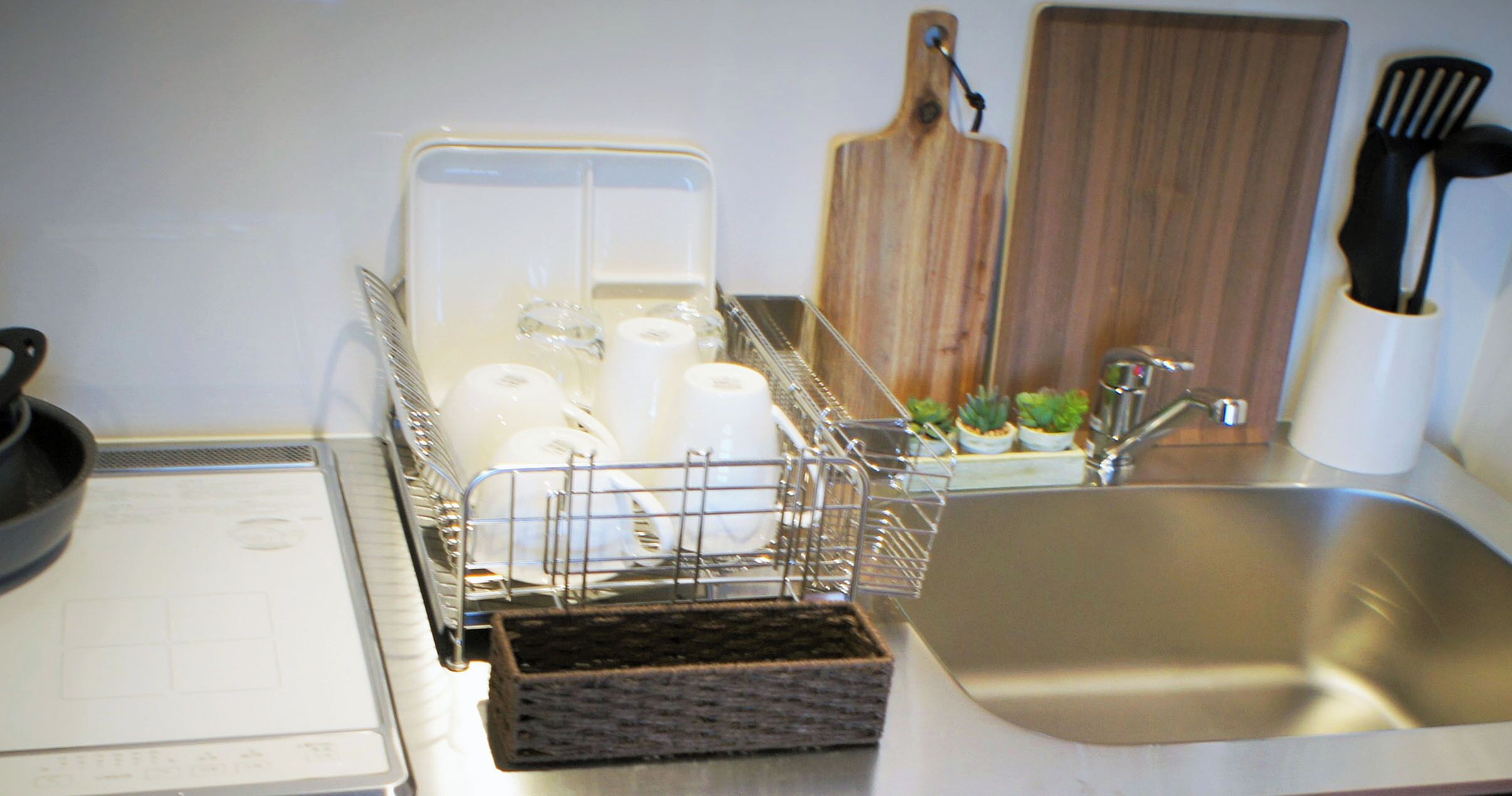 A kitchen with a dishwasher, sink, wooden cutting board, and utensils.