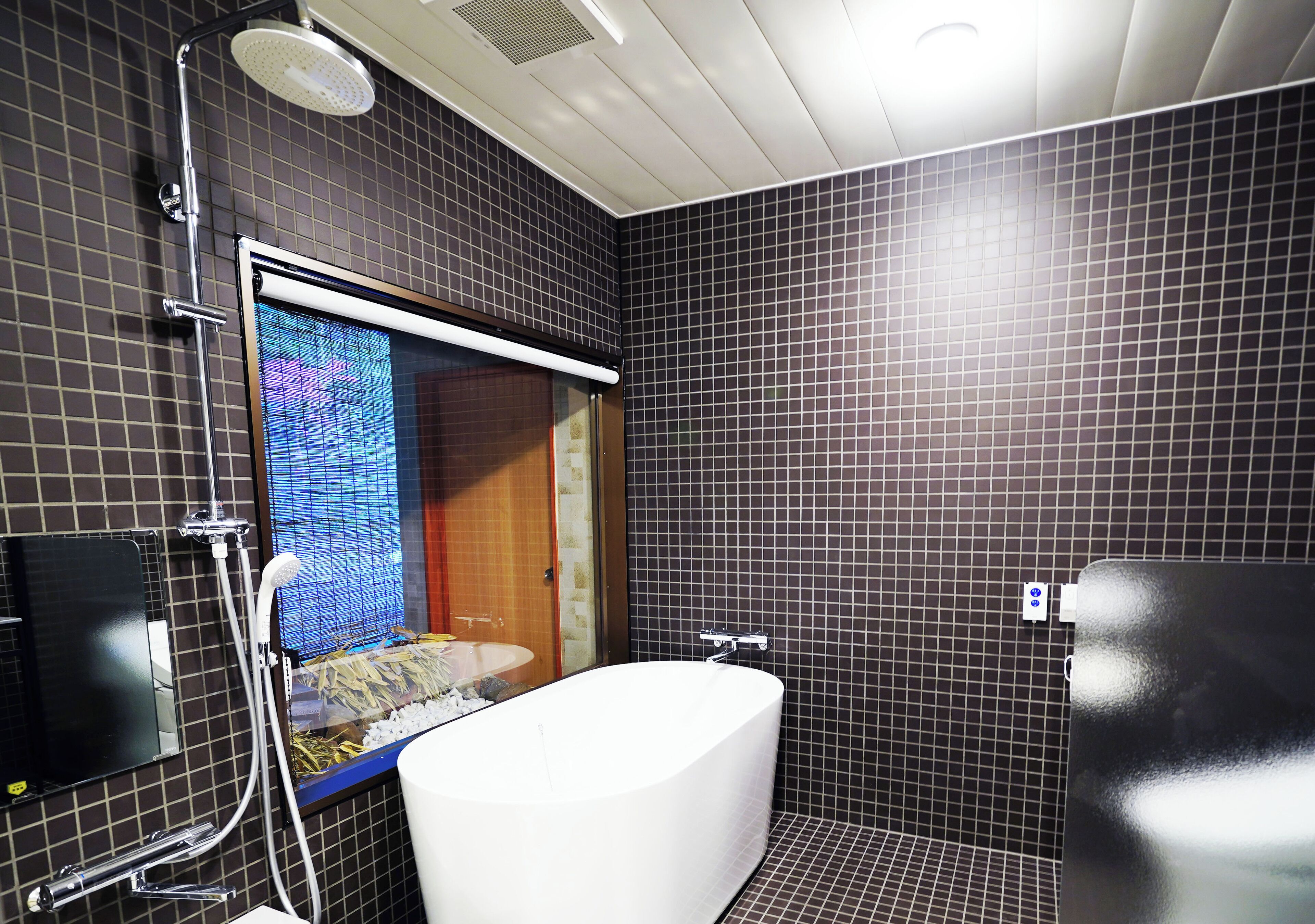 Un baño moderno con una bañera grande, un cabezal de ducha y una pared con azulejos.