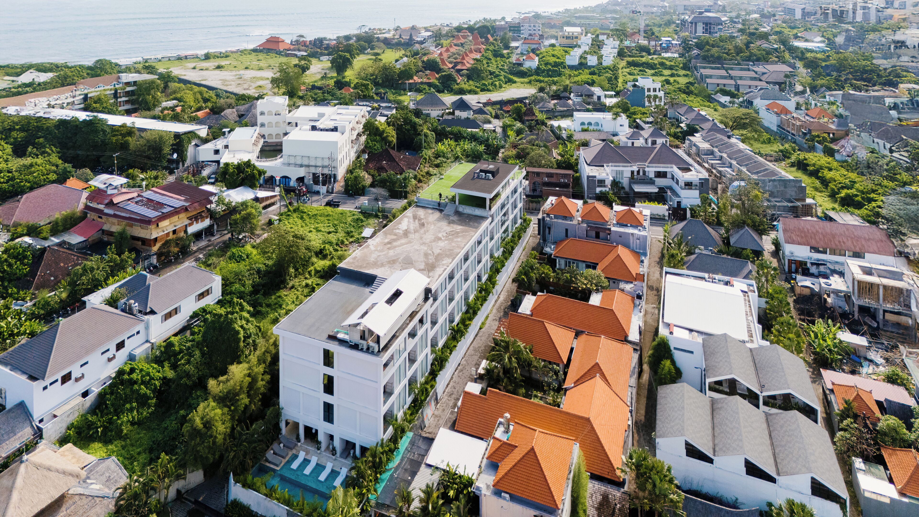 Zona residencial amb cases modernes, una piscina i vista al mar.