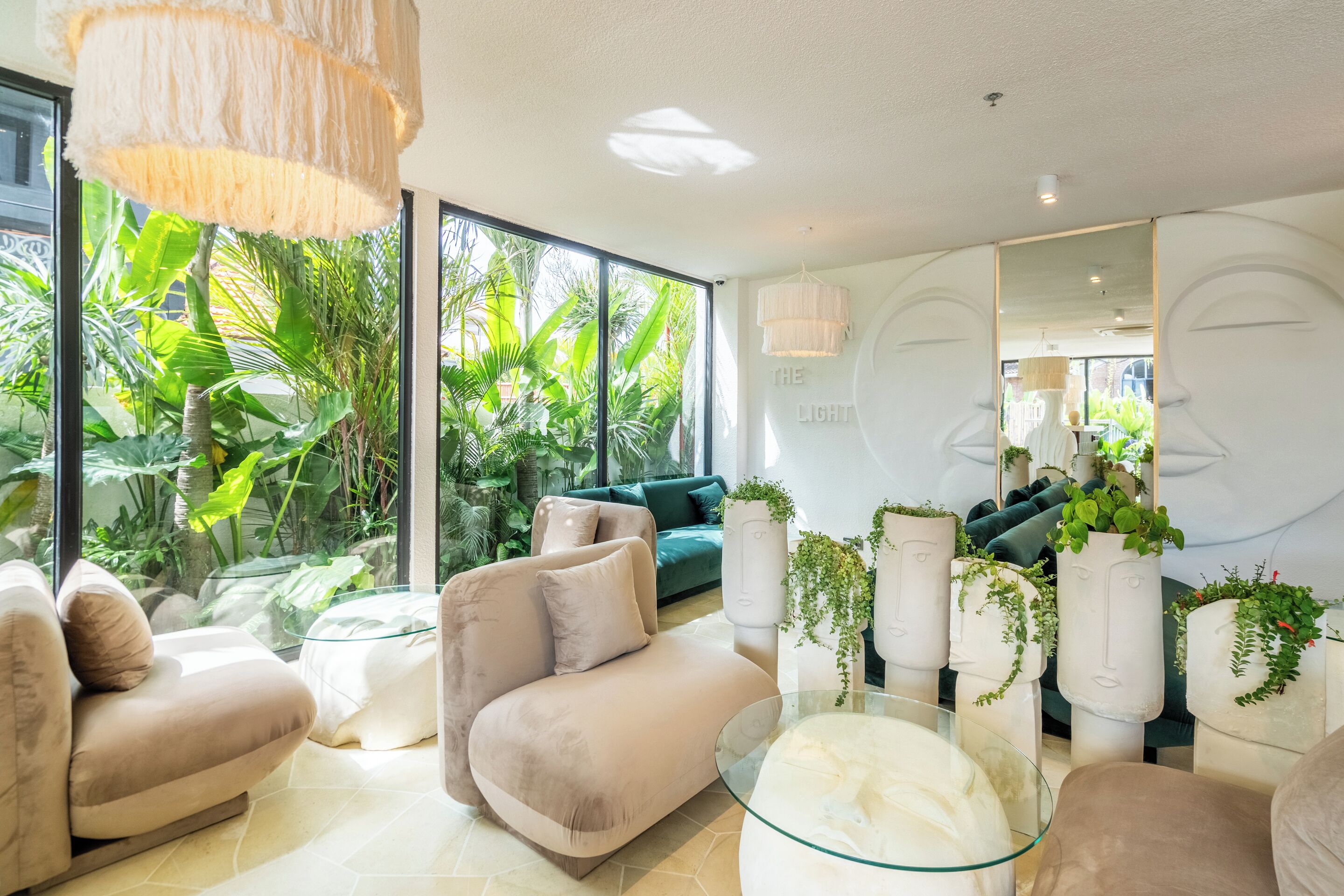A modern living room with a large window, a green sofa, and a glass coffee table.