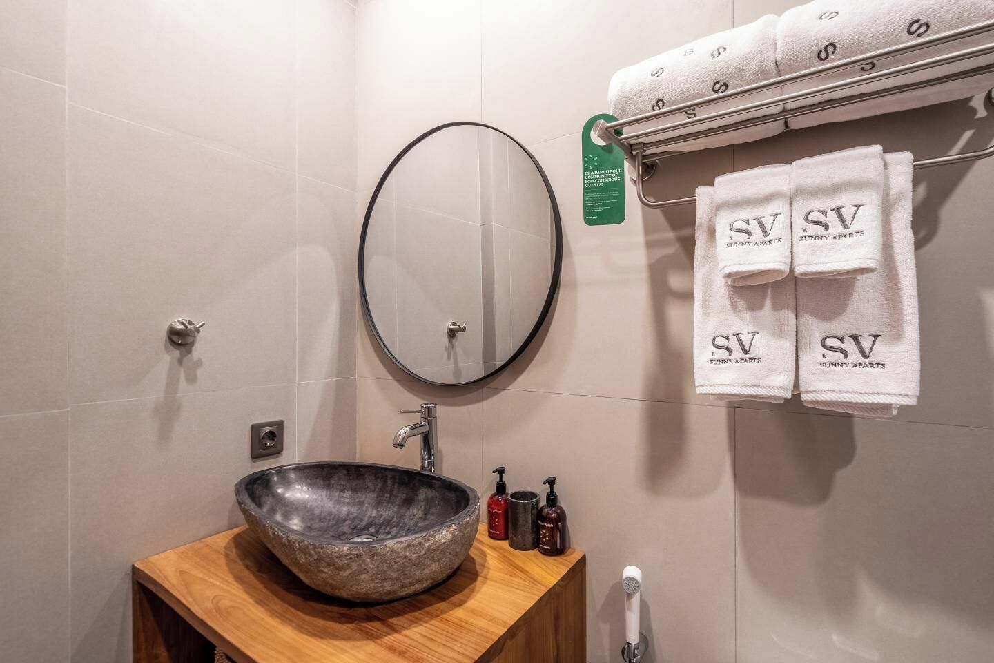 Ein Badezimmer mit einem runden Spiegel, einem Holzbalkon und einem Handtuchhalter mit Handtüchern.