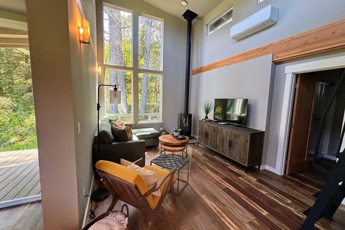 Un salon moderne doté d’une cheminée, d’un téléviseur et d’une grande fenêtre donnant sur un espace verdoyant.