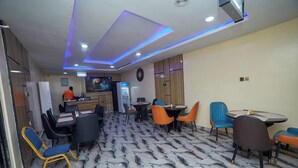 Un restaurante con suelo de mármol, diseño moderno del techo y diversas opciones de asientos, incluidas sillas y mesas.