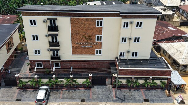 Un edificio de varios pisos con un cartel llamativo que indica "Masters Class", ofreciendo suites y apartamentos.