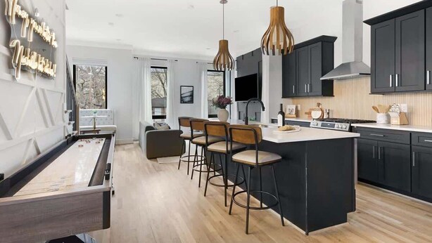A modern kitchen with a bar area, wooden bar stools, and pendant lighting. - The Chorus & The Duet - Mins from Downtown! (Nashville)