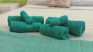 Una cama con un edredón color turquesa, una toalla color turquesa y una almohada con un diseño de rostro.