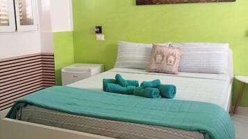 A bedroom with a bed, a nightstand, a wall-mounted painting, and a window with blinds.