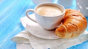 A cup of coffee and a croissant on a white napkin. - Da Nina (Lascari)