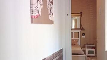 Ein Flur mit Wandverkleidung, einem Bett mit Nachtisch und einem Spiegel.
