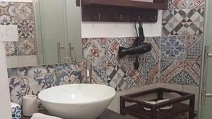 A bathroom with a large white sink, a mirror, a towel rack, and patterned tiles. - Da Nina (Lascari)