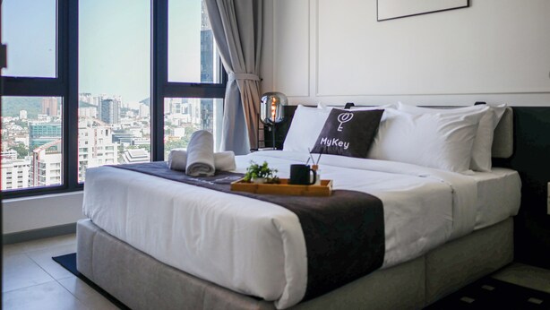 Una camera d'albergo moderna con un letto grande, vista sulla città e un quadro appeso al muro.