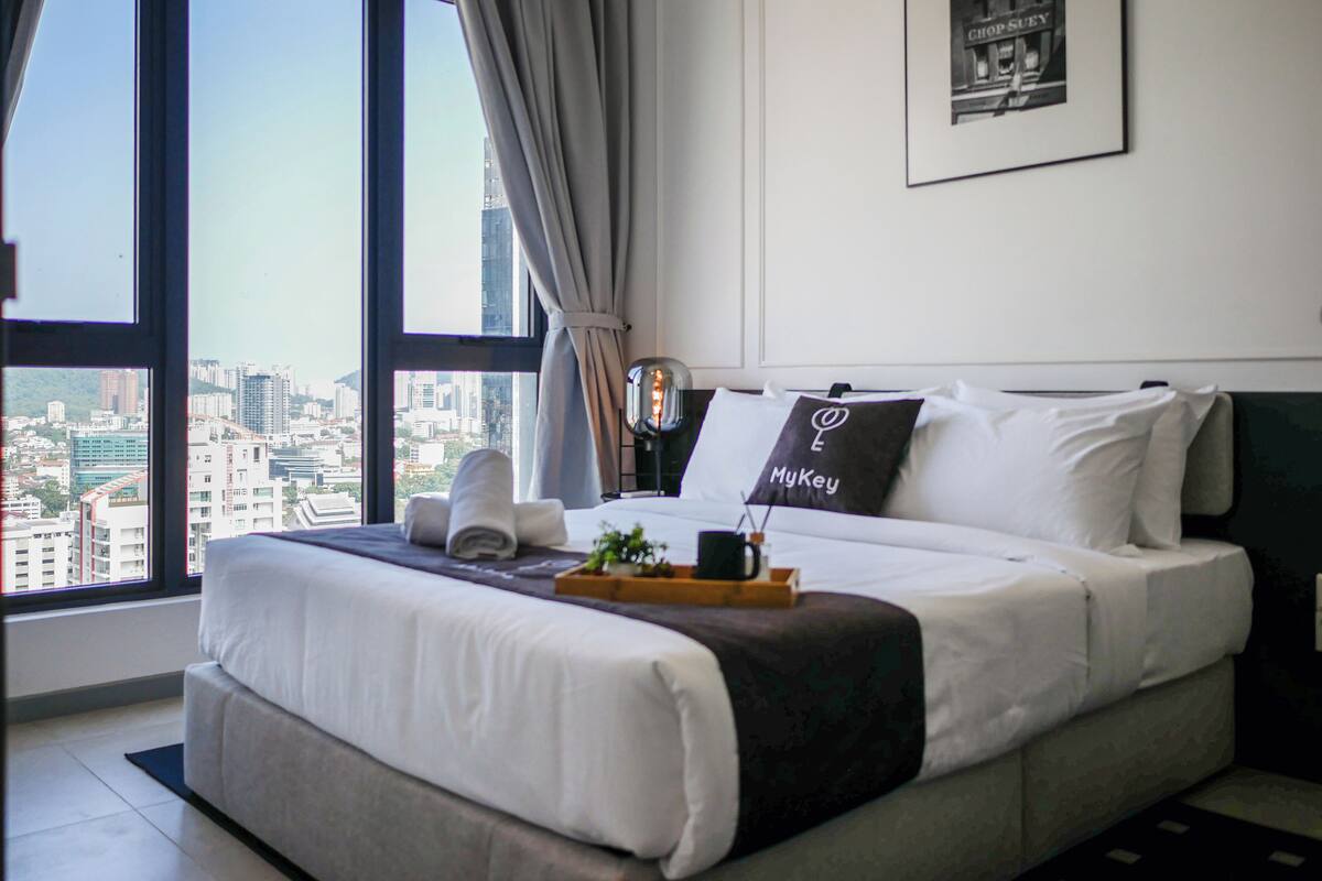 Ein modernes Hotelzimmer mit einem großen Bett, Blick auf die Stadt und einem gerahmten Bild an der Wand.